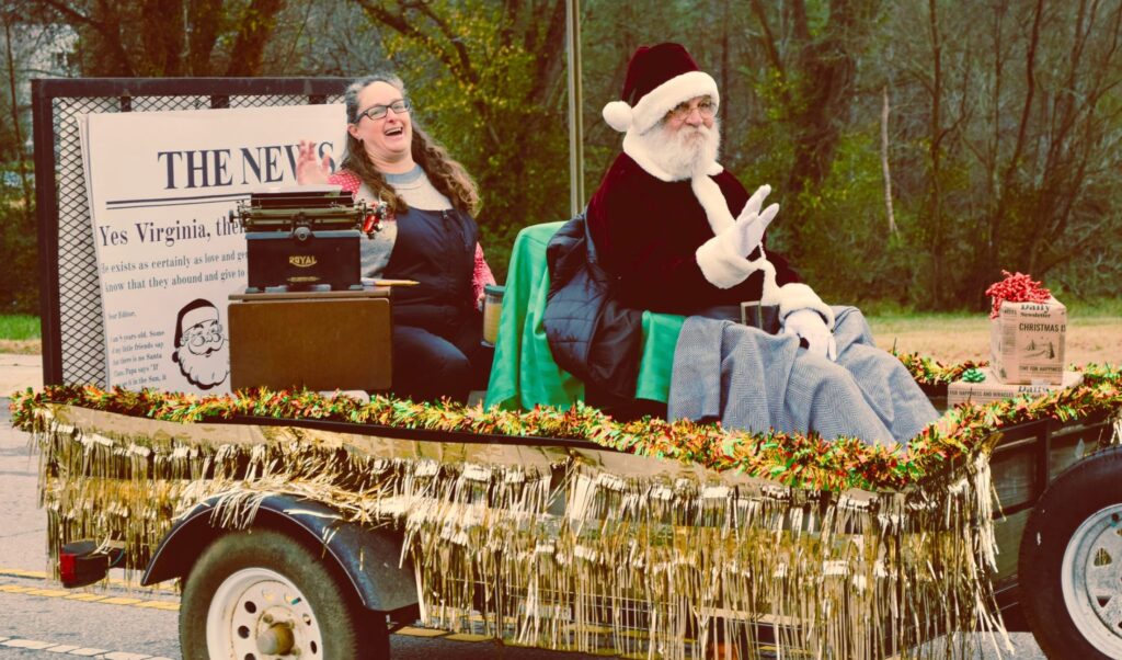 Shannon Moretz rides a parade vehicle with Santa.